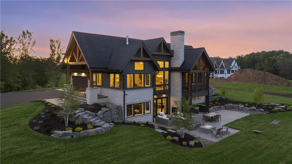 Aerial view of an upscale suburban home at twilight with a spacious driveway and well-maintained lawn.
