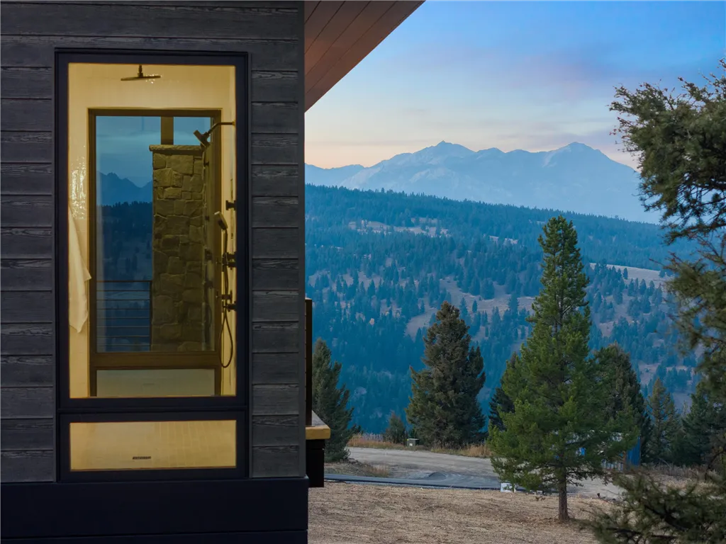 Wooden cabin by a snowy mountain lake at dawn.