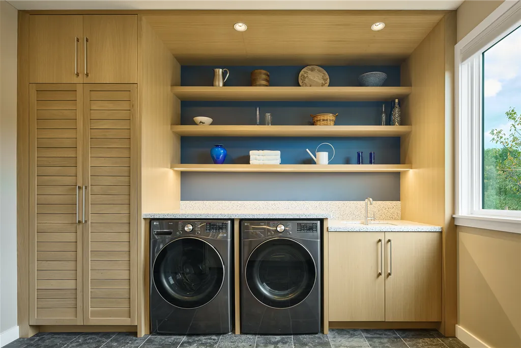Modern laundry room with cabinets, refrigerator, and wooden furniture.
