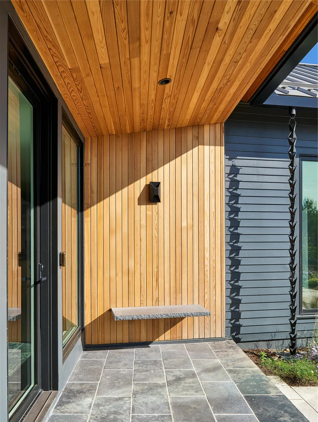 Entrance of a contemporary luxury home with wooden accents and large windows.