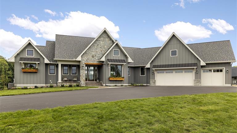 Luxury suburban home with a spacious driveway and well-maintained lawn.