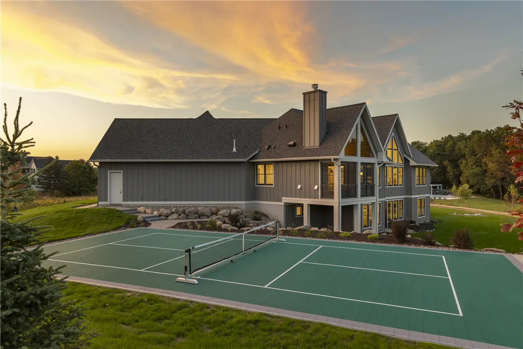Luxurious mansion with a private tennis court and lush lawn at twilight.