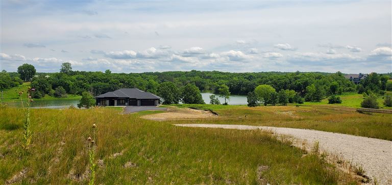 Countryside landscape with a farmhouse, river, and trees in summer.