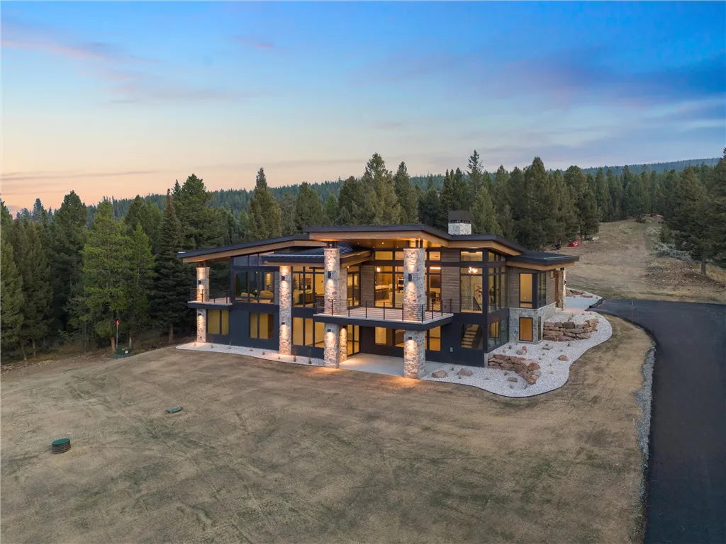 Wooden cabin in a mountainous landscape surrounded by trees.